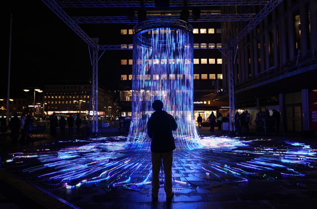 En siluett framför ljuskonstverket Flux på ljusfestivalen Nobel Week Lights 2024
